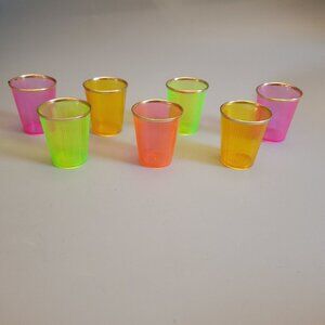 Vintage 1950s set of colorful 2 ounce plastic shot glasses with gold metal rims.
